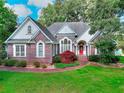 Inviting brick home with a red front door, manicured lawn, and mature trees in a residential area at 1595 Lake Lucerne Rd Sw, Lilburn, GA 30047