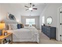 Bright bedroom featuring a tufted headboard, ceiling fan, and a dresser with a round mirror at 2735 Maple Park Pl # 32, Cumming, GA 30041