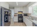 Bright kitchen with white cabinets, black appliances, and wood-look floors at 3120 Westwood Dr, Acworth, GA 30102