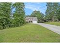 Inviting home showcasing stone accents, gray siding, a sprawling lawn, and mature trees at 27 Rose Brooke Cir, White, GA 30184