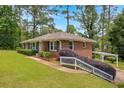 Brick house with landscaped yard, carport, and a set of stairs leading to the front door at 2320 Tilson Cir, Decatur, GA 30032