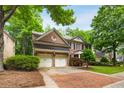 Inviting brick home with an attached two-car garage and a manicured lawn with trees at 3227 Collier Gate Se Ct, Smyrna, GA 30080