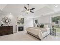Calm, bright primary bedroom suite with a tray ceiling, ceiling fan, and a cozy fireplace at 255 Broken Lance Pl, Johns Creek, GA 30022