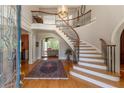 Grand foyer featuring a curved staircase with wrought iron railings and gleaming hardwood floors at 8470 Lazy Oaks Ct, Atlanta, GA 30350