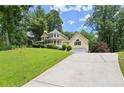 Charming yellow house with a wraparound porch, garage, and a long driveway at 1713 Dudley Dr, Woodstock, GA 30188