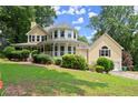 A charming yellow home with a wraparound porch and a well-manicured lawn at 1713 Dudley Dr, Woodstock, GA 30188