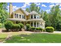 Charming yellow house with wraparound porch, black shutters, and landscaped front yard at 1713 Dudley Dr, Woodstock, GA 30188