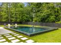 Beautiful backyard pool featuring sleek tile, a buddha statue, and a dark wood privacy fence at 185 Pebble Trl, Alpharetta, GA 30009
