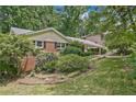 Traditional brick home featuring a covered parking area, lush greenery, and well-manicured lawn at 3327 Spring Meadow Ct, Tucker, GA 30084