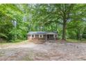 View of home nestled in a wooded area, featuring white trimmed windows and gravel parking area at 143 Longview Rd, Fayetteville, GA 30214
