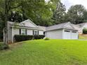 Well-manicured lawn surrounds this one-story home with an attached two-car garage and neutral siding at 225 Magnolia Tree Ct, Johns Creek, GA 30022