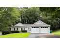 Single story home with a two-car garage, black shutters and green lawn at 225 Magnolia Tree Ct, Johns Creek, GA 30022