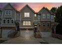 Charming townhomes featuring a brick facade, individual garages, and inviting front entrances at dusk at 4173 Chatham Ridge Dr, Buford, GA 30518