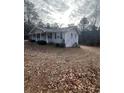 Inviting single-story home showcasing gray siding, black shutters and a gravel driveway surrounded by trees at 6540 Old White Mill Road Rd, Fairburn, GA 30213