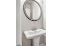Elegant powder room featuring a pedestal sink, round mirror, and stylish fixtures at 181 Dewy Rd # 70, Lilburn, GA 30047