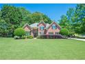 Traditional brick home with a lush green lawn, mature landscaping, and a welcoming facade at 7045 Grand View Way, Suwanee, GA 30024