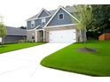 A bright home exterior featuring a well-maintained yard, white garage door, and stone accents at 3855 Saddle Bag Ct, Dacula, GA 30019
