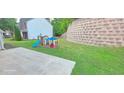 Backyard featuring a play structure with slide and grass with retaining wall in background at 779 Avonley Creek Trce, Sugar Hill, GA 30518