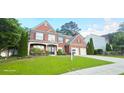 Beautiful brick home featuring a manicured lawn and a 'For Sale' sign at 779 Avonley Creek Trce, Sugar Hill, GA 30518