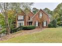 Charming two-story brick home with well-manicured landscaping, shutters, and an American flag at 3565 Hickory Branch Trl, Suwanee, GA 30024