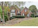 Charming two-story brick home with well-manicured landscaping, shutters, and an American flag at 3565 Hickory Branch Trl, Suwanee, GA 30024