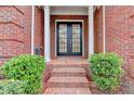 Inviting front entrance with brick steps, black double doors, trimmed bushes, and brick walls at 3565 Hickory Branch Trl, Suwanee, GA 30024