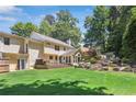 Expansive backyard featuring a deck, stairs up a rockery hill, lush lawn, and mature trees providing privacy at 3837 Fenway Xing, Marietta, GA 30062