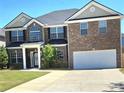 Two story brick home featuring a well manicured front yard and attached two car garage at 5030 Mundy Dr, Cumming, GA 30028