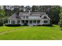 Expansive backyard view of a home with a full-length porch, showcasing lush greenery and outdoor living space at 625 W Lake Dr, Oxford, GA 30054