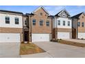 Well-maintained townhomes with brick and siding exteriors, each featuring an individual garage at 8210 Tiger Way, Riverdale, GA 30296