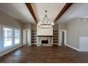 Spacious living room with stone fireplace, wood beams, hardwood floors and modern lighting fixture at 2226 Upper Burris Rd, Canton, GA 30114