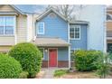 Charming blue townhouse with a red door, brick accents, and mature landscaping at 3263 Long Iron Pl, Lawrenceville, GA 30044
