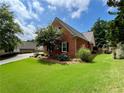 Exterior view of brick house, with a green lawn and well maintained landscaping at 5220 Wild Cedar Dr, Buford, GA 30518
