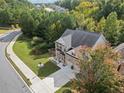 Aerial view of a brick home with a two-car garage, surrounded by lush greenery and a well-maintained lawn at 3865 Brookhollow Dr, Douglasville, GA 30135