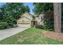 Well-manicured front lawn with mature trees framing a two-story home with a spacious driveway at 265 Lee River Cv, Suwanee, GA 30024