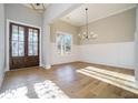 Elegant foyer boasts gleaming hardwood floors, a stylish chandelier, and a stunning wood double-door entry with decorative glass at 2200 Upper Burris Rd, Canton, GA 30114