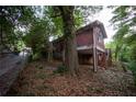 View of elevated red home with partial stone foundation surrounded by foliage and a chain-link fence at 1398 Christmas Ne Ln, Atlanta, GA 30329