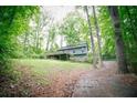 Exterior view of a single Gathering home with a deck surrounded by mature trees and lush greenery at 4190 Heather Way, Cumming, GA 30041