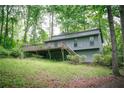 Exterior view of a single Gathering home with a deck surrounded by mature trees and lush greenery at 4190 Heather Way, Cumming, GA 30041