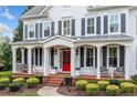 Charming white facade with covered porch, brick steps, and manicured landscaping at 6219 Creekstone Path, Cumming, GA 30041