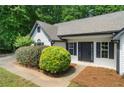 Inviting front porch of a white home featuring manicured bushes, black shutters, and a black front door at 545 Willow Creek Dr, Temple, GA 30179