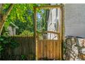 View of side yard through the wooden fence gate with ivy, green trees, and a brick wall of home at 2133 Trailwood Rd, Decatur, GA 30032