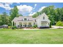 Charming white farmhouse with a lush front lawn and inviting front porch area at 124 White Oak Trl, Cumming, GA 30028