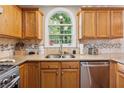 Bright kitchen featuring stainless steel appliances, granite counters, and a charming arched window over the sink at 1679 Summit Place Way, Loganville, GA 30052
