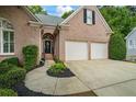 Inviting brick home with a two-car garage, landscaped garden, and a paved walkway at 1444 Merrifield Ln, Marietta, GA 30062
