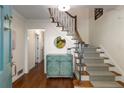 Bright entryway with hardwood floors, staircase, and a decorative cabinet with a round mirror at 6990 Brandon Mill Nw Rd, Atlanta, GA 30328