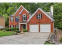 A view of a charming two-story brick home with a two-car garage, and basketball hoop in driveway at 135 Clubhouse Nw Dr, Kennesaw, GA 30144
