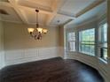 Elegant dining room boasts coffered ceilings, dark wood floors, and a bay window at 381 Plymstock Dr, Mcdonough, GA 30253