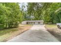 Scenic view of a white brick home nestled among lush trees with a long driveway at 703 Alvis Ln, Norcross, GA 30093