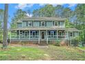 Inviting two-story home features a spacious front porch, brick foundation, and lush lawn at 3392 Inns Brook Way, Snellville, GA 30039